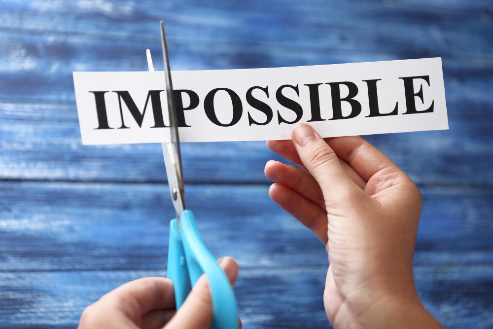 manos recortando la palabra impossible